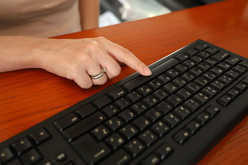 Black Computer Keyboard with female hands typing on it inside an office