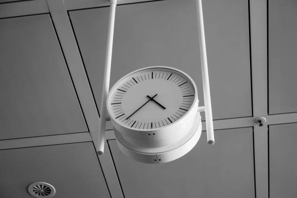 Big round analog clock handing from the ceiling inside an international airport.