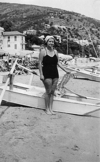 Cute young woman posing at the beach with swimsuit. 1930s black and white film. Alassio, Liguria. Italy