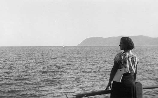 Cute young woman relaxing on the seafront. 1930s black and white film. Alassio, Liguria. Italy