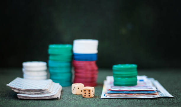 istock Casino poker chips stack with playing cards, dice and money on green felt background 1272635375