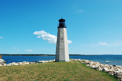 The Gladstone Lighthouse in the Upper Peninsula of Michigan on the shores of the Great Lake Michigan on Green Bay. The waters are visible to the horizon.  The Gladstone Michigan Lighthouse stands tall on the end of rocky breakwater.