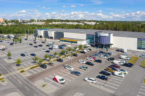A large parking lot with cars in front of a shopping center with various stores.