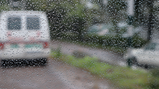 Ambulance in rain shot through glass window with closeup shot of rain drops on glass
