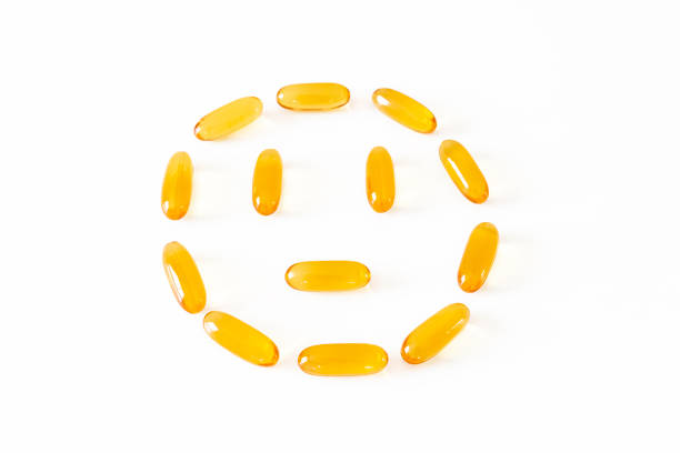 Smiley face from gelatin softgels Capsules of Omega-3 fats on white background. Eicosapentaenoic acid and fish oil. Organic dietary supplements concept. Selective focus, backlight Smiley face from gelatin softgels Capsules of Omega-3 fats on white background. acid and fish oil. Organic dietary supplements concept. eicosapentaenoic acid stock pictures, royalty-free photos & images