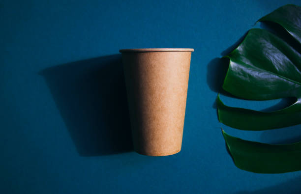 istock Eco friendly craft paper cup on green background with monstera leaf. 1272650224