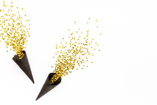 istock Black waffle cones with golden confetti tinsel isolated on white background. Flat lay, top view minimal festive concept 1272651205