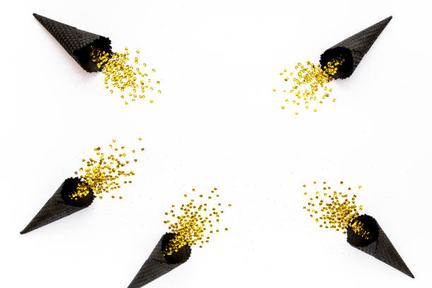 istock Black waffle cones with golden confetti tinsel isolated on white background. Flat lay, top view minimal festive concept 1272651481