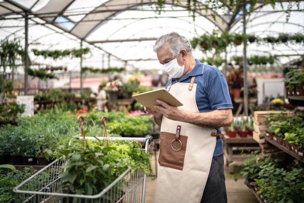 istock Florist man using digital tablet at a garden shop wearing a face mask 1272652855
