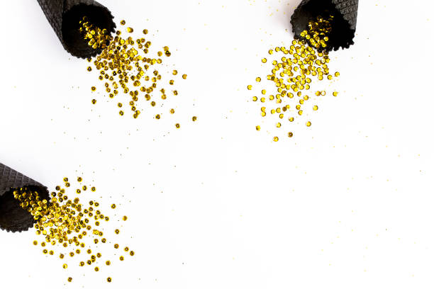 istock Black waffle cones with golden confetti tinsel isolated on white background. Flat lay, top view minimal festive concept 1272663736
