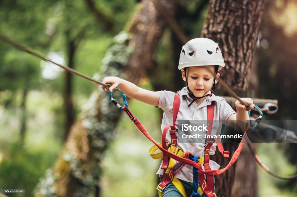 Happy child enjoying activity in a climbing adventure park on a summer day Child Stock Photo