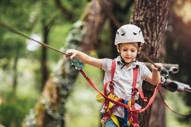 happy child enjoying activity in a climbing adventure park on a summer day - tree skill nature horizontal imagens e fotografias de stock
