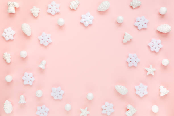 Christmas frame with white christmas snowflakes on pink background. Christmas composition, wallpaper. Flat lay, top view