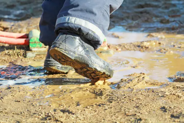 children with rubber boots in a puddle