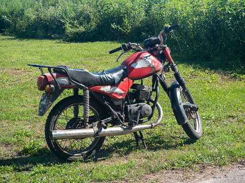 an old red motorcycle on a bright summer day in the village