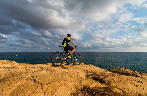 mountain biker looks at the sea from the cliff- space for text