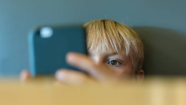 Thoughtful kid holding smartphone. Selective focus stock photo