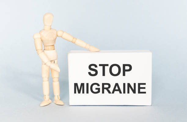 istock Text Stop Migraine on a white box on a light blue background with a wooden human figurine. 1272671802