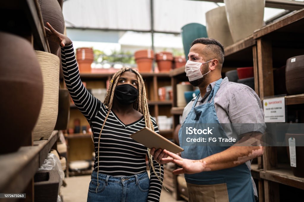 Salesman helping client shopping for plant vase in a garden center Customer Stock Photo