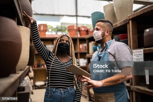 Salesman Helping Client Shopping For Plant Vase In A Garden Center Stock Photo - Download Image Now