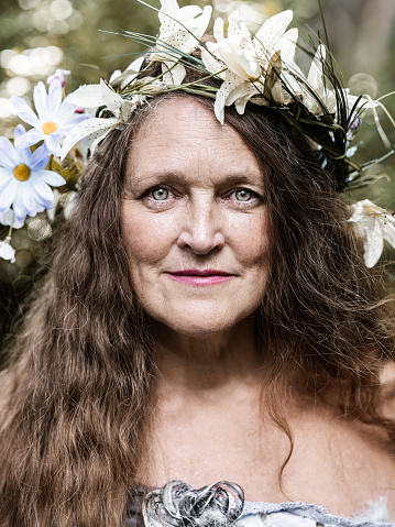 Portrait of senior woman dressed as fairy. Exterior of beautiful back yard garden.