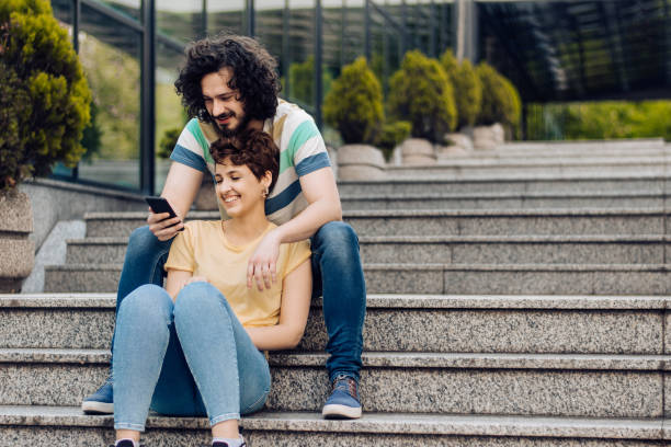 istock Young couple sitting outdoors, shopping online and having fun 1272675848
