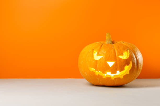 istock Glowing Halloween pumpkin on a orange background. 1272678306