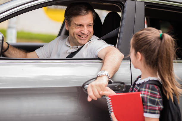 istock Happy man laughing when holding his daughter's hand from the car window before school 1272681439