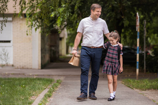 istock Man hugging daughter as they are walking from school 1272681544