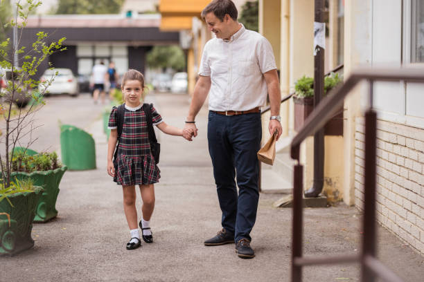 homme heureux avec le déjeuner emballé dans le sac en papier retenant les mains de sa fille sur leur chemin à l’école - paper bag bag packed lunch paper photos et images de collection