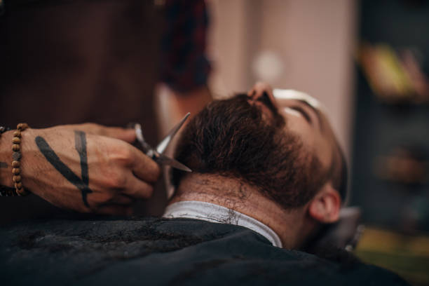 istock Male barber cutting client's beard with scissors 1272683448