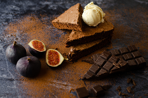 Swedish Sticky Chocolate Cocoa Cake Kladdkaka with Vanilla Ice cream, Figs and dark chocolate on a Dark Stone background