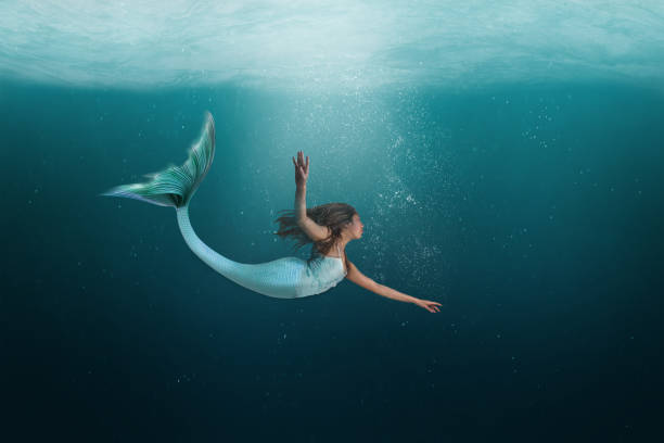 Underwater Mermaid Swimming Gracefully in the Ocean Mermaid with long tail swimming under the deep waters of the ocean. tail photos stock pictures, royalty-free photos & images