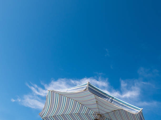 istock Striped Beach Umbrella Against a Blue Sky 1272695394