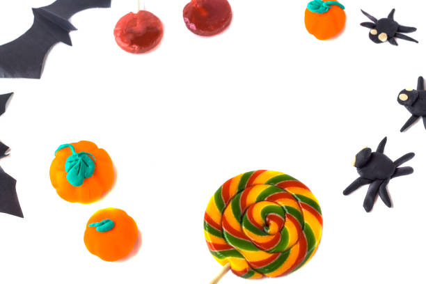 istock Halloween decoration. Frame from pumpkins and spiders hand made from plasticin, paper bats and candies with copy space on a white wooden background. 1272697545