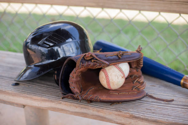 la saison de baseball est là.  chauve-souris, gant, casque et balle sur le banc de pirogue. - dugout baseball bench bat photos et images de collection