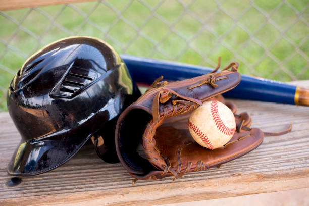 la saison de baseball est là.  chauve-souris, gant, casque et balle sur le banc de pirogue. - dugout baseball bench bat photos et images de collection