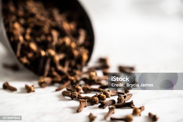Scoop Of Cloves On A White Marble Surface Stock Photo - Download Image Now - Clove - Spice, Color Image, Copy Space