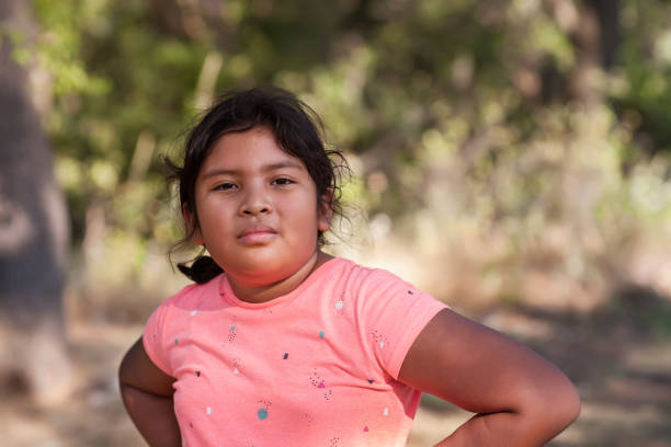 A young Latino girl with arms resting on her hips and expressing an aggressive attitude, hostile or intimidating. stock photo