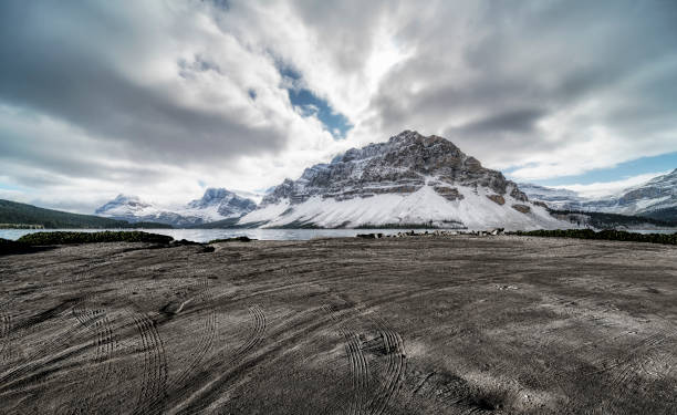 spiaggia sporca vuota con tracce contro le montagne rocciose canadesi - autumn road landscape mountain foto e immagini stock