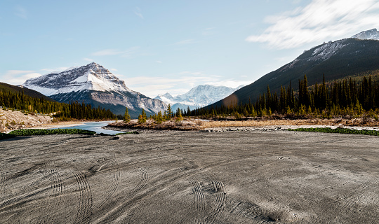 empty dirt beach with traces against Canadian Rockies, AB, Canada.