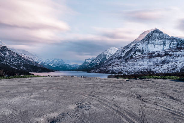 empty dirt beach with traces against Canadian Rockies, AB, Canada.