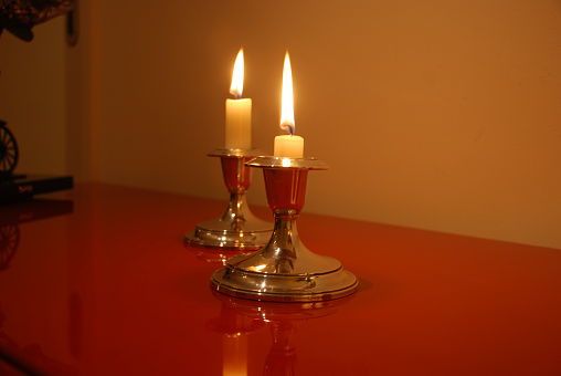 Two candles burning in silver candlesticks. Wide Shot.