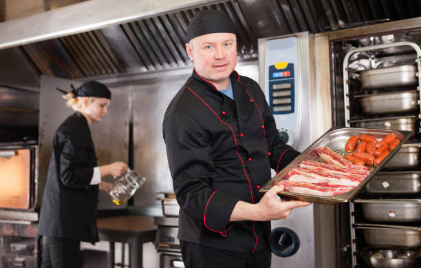 istock Chef holding baking tray with raw meat products 1272714110