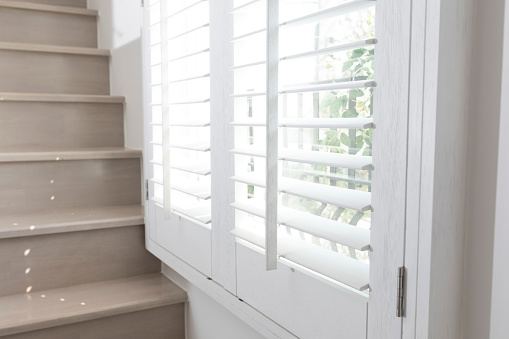 Close up view of window with horizontal blinds. White Roller Blinds or Louver curtains at the glass window.
