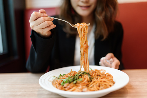 Close-up of woman eating pasta.