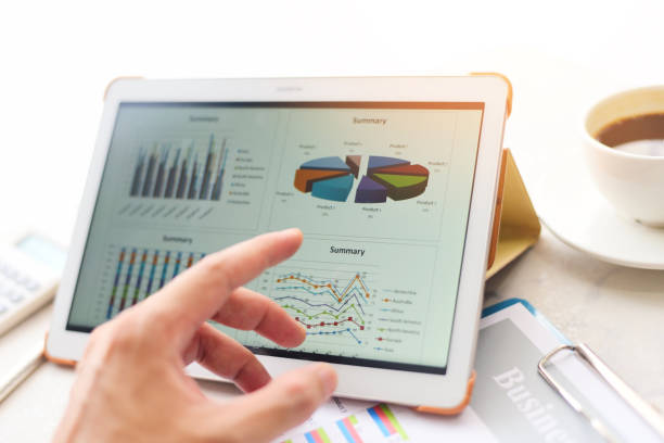 istock Business graphs chart on a tablet computer technology on the table with coffee cup on desk and calculator - Sale report money analyzing 1272721887