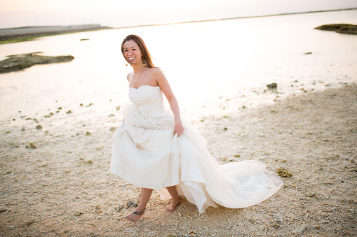 A young Japanese woman in a wedding dress on the beach at sunset in Okinawa, Japan