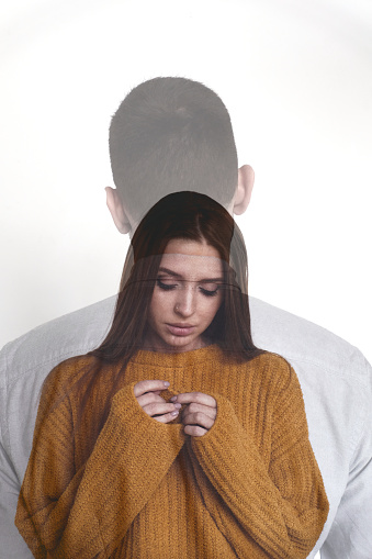 Portrait of young beautiful woman standing with her back to unrecognizable man and looking at hands sadly, double exposure