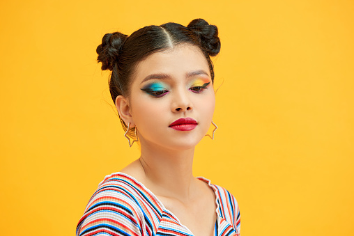 Positive asian girl in cropped top posing on yellow background.